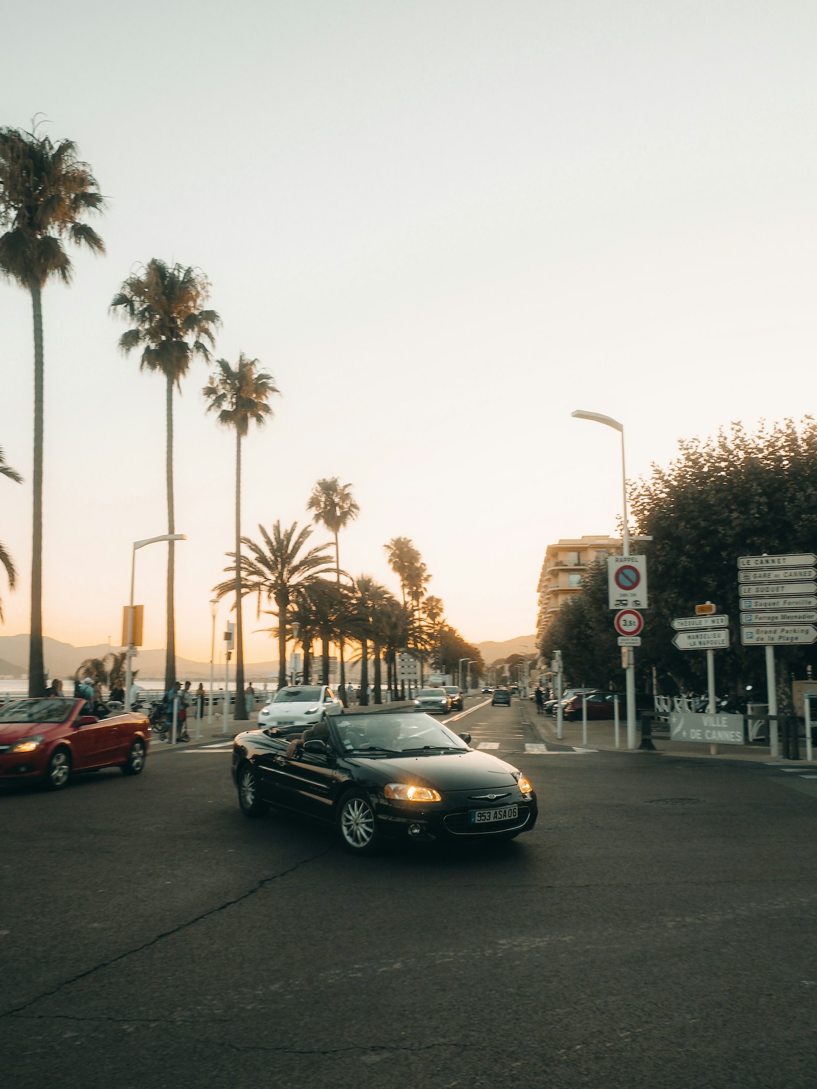 Convertibles on a Riviera boulevard at golden hour