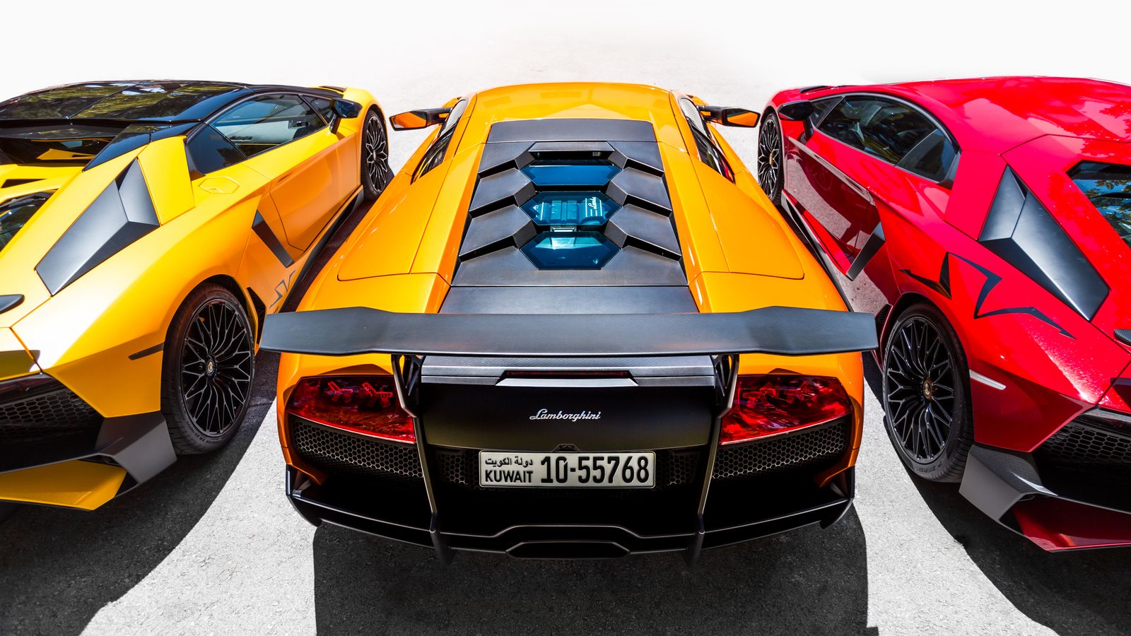 Three supercars in vivid colour under bright light
